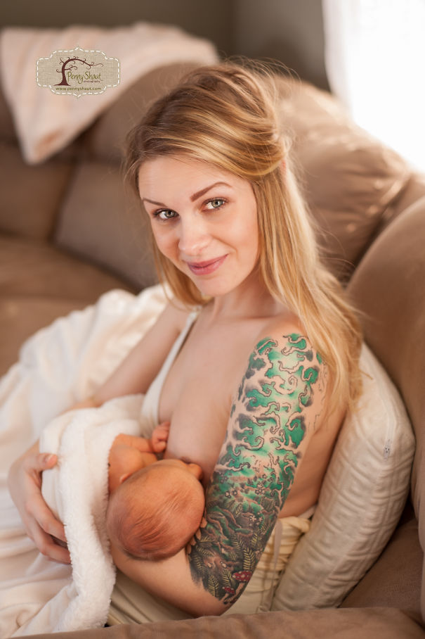 Tattooed parent lovingly holding a baby on a couch, creating a beautiful family moment together.