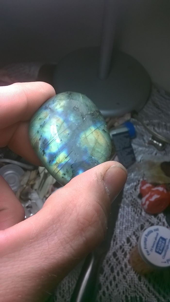 Hand holding a beautiful mineral with iridescent colors in natural light.