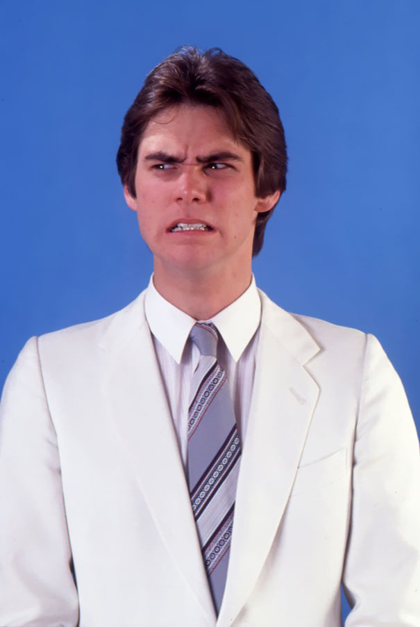 Young Jim Carrey in a white suit making a manic facial expression during early celeb impressions in 1992.