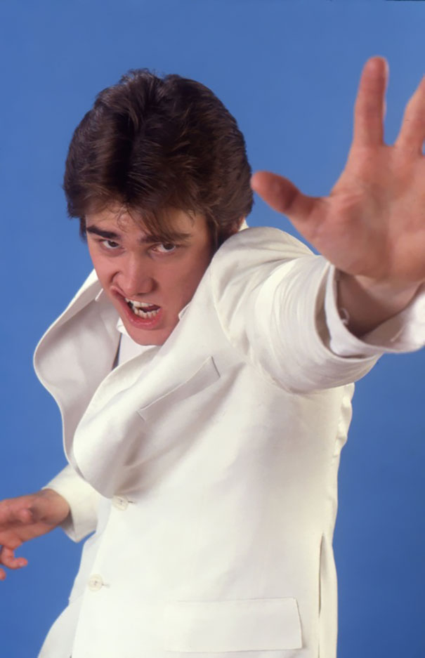 Young Jim Carrey in a white suit striking a dynamic pose during his manic celeb impressions in 1992. Young Jim Carrey in a white suit striking a dynamic pose during his manic celeb impressions in 1992.