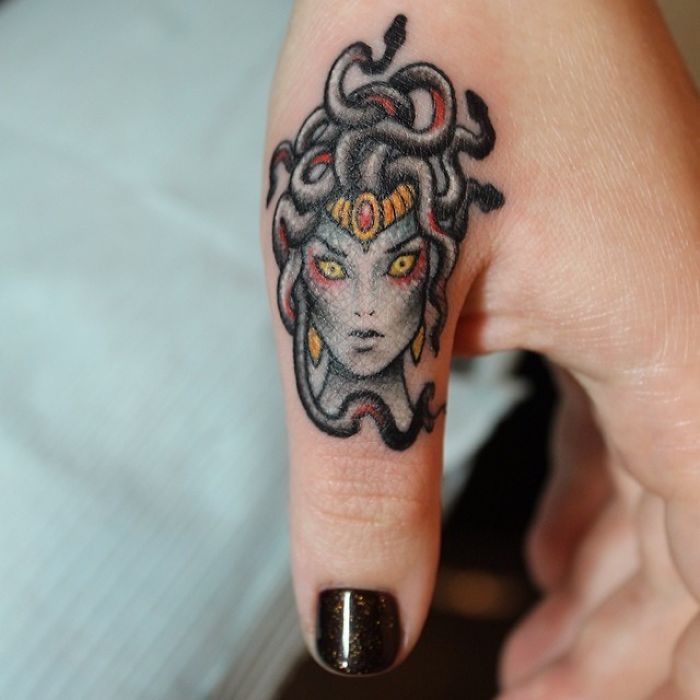 Close-up of Medusa finger tattoo, showcasing intricate details and colorful design, highlighting newest tattoo trend.