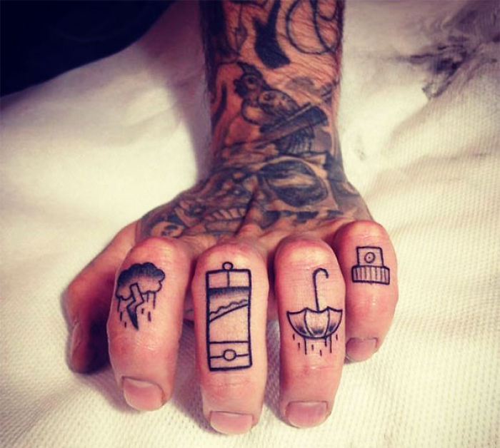 Close-up of finger tattoos featuring various designs, highlighting the newest trend in body art.