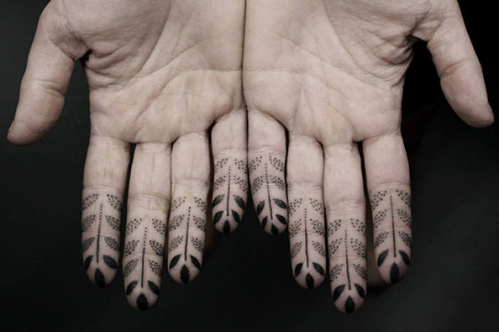 Intricate finger tattoos featuring leaf designs on the fingertips displayed on open palms.