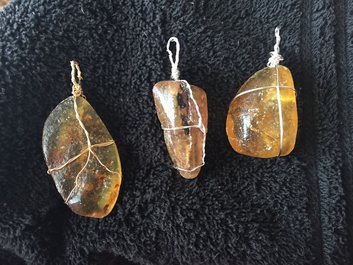 Three beautiful minerals wrapped in wire on a dark fabric background.