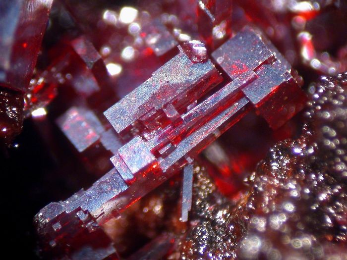 Close-up of extremely beautiful red mineral crystals displaying geometric shapes and reflective surfaces.