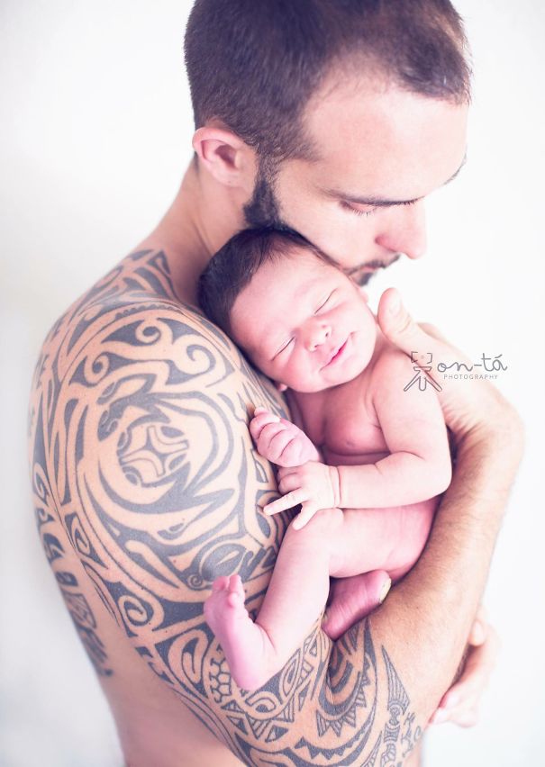 Tattooed parent tenderly holding their newborn, showcasing the bond between tattooed parents and their babies.