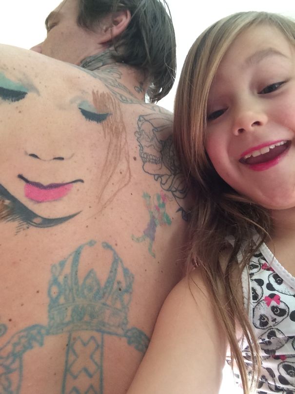 Child with tattooed parent, showcasing body art and a joyful expression together.