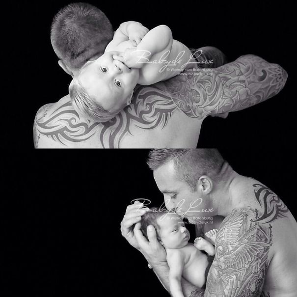 Tattooed parent holding a baby, showcasing a contrast of inked skin and soft infant features in black and white.