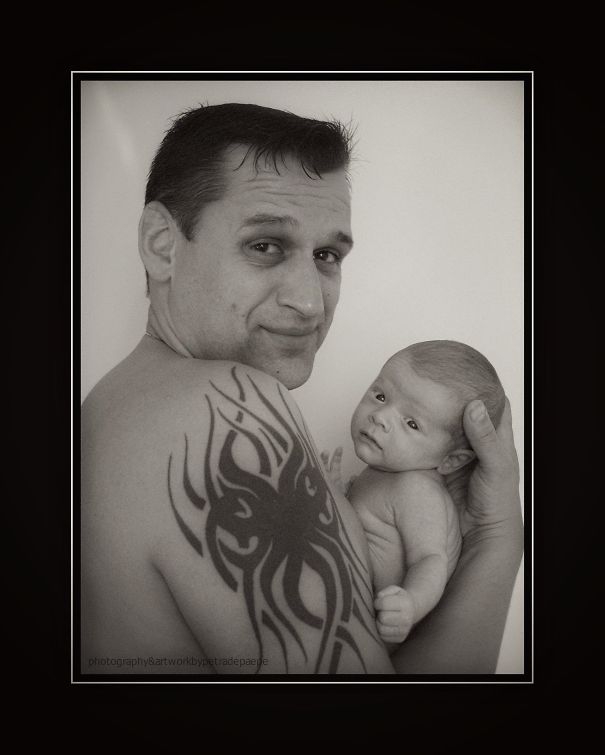 Tattooed parent holding a baby, showcasing a beautiful bond together.
