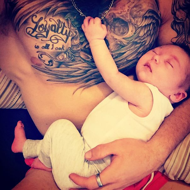Baby sleeping on tattooed parent's chest, showcasing beautiful bond and tattoos.