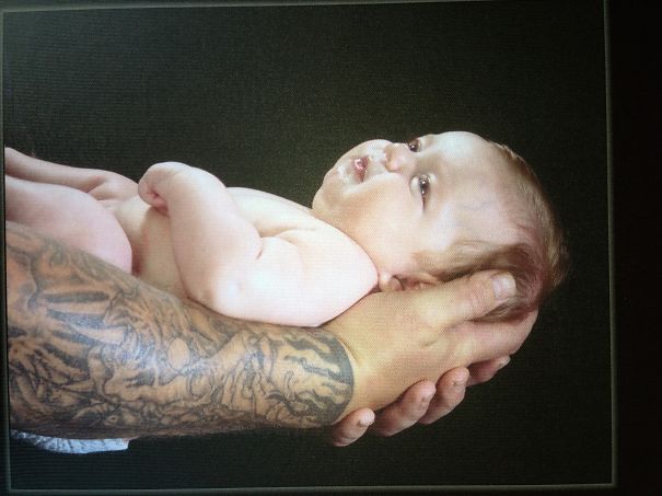 Tattooed parent gently holding a baby, showcasing a beautiful bond.