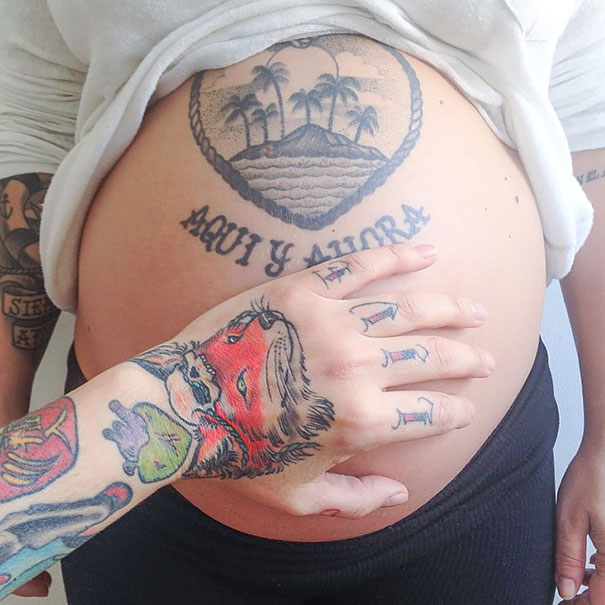 Tattooed parent caressing pregnant belly with tattoos, embracing the beauty of parenthood.