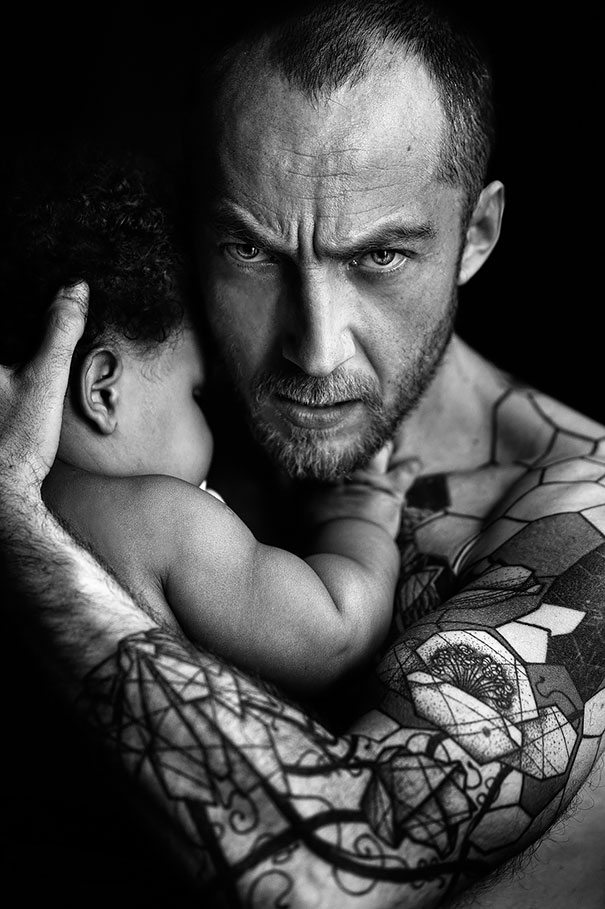 Tattooed parent holding a baby, showcasing beautiful body art and family connection.
