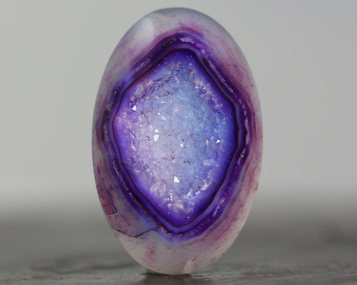 Purple geode displaying intricate crystal formations in its center.