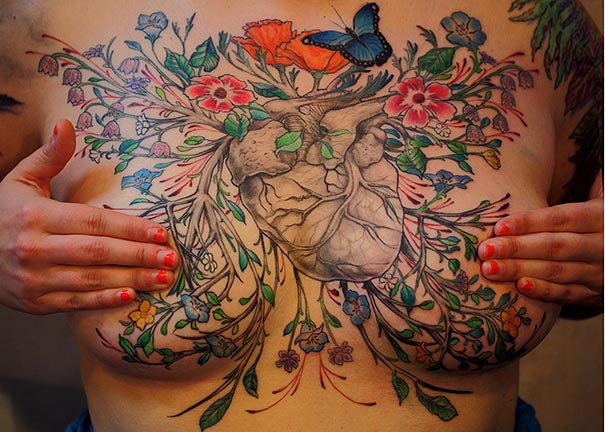 Breast cancer survivor's mastectomy scar covered with a vibrant, floral tattoo design.