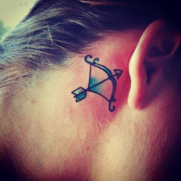 Bow and arrow tattoo on an ear showcasing creative ear tattoo design.