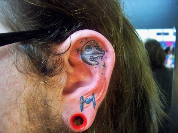 Creative ear tattoos featuring a space theme with celestial elements and a spaceship.