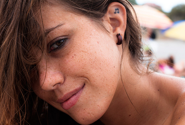 Close-up of a woman's ear tattoo featuring a small music note.