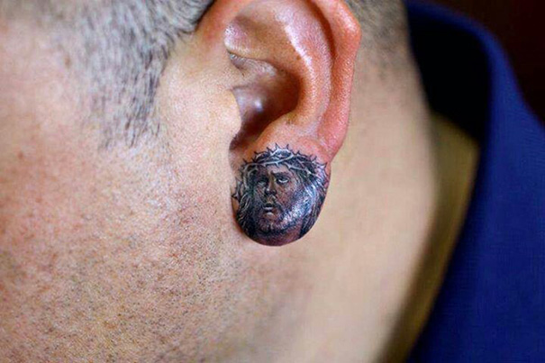 Creative ear tattoo depicting a detailed artwork on the earlobe.