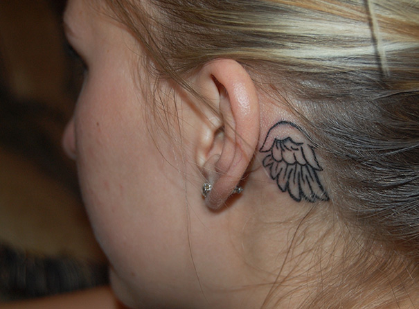 Creative ear tattoo featuring an angel wing design behind the ear.