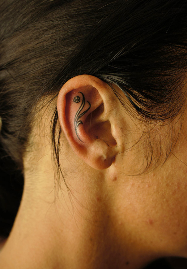 Creative ear tattoo featuring elegant lines and small floral detail.