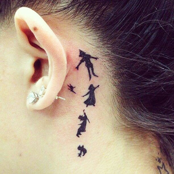 Creative ear tattoo featuring small silhouette designs behind the ear.