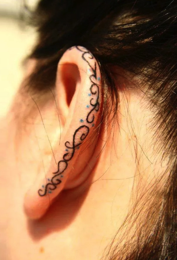 Ear with creative tattoo design along the edge.
