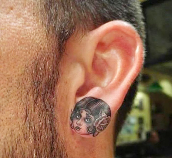 Creative ear tattoo with a detailed illustration of a woman's face on the earlobe.