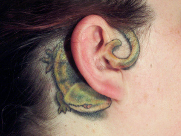 Colorful lizard ear tattoo with curled tail around the ear. Creative ear tattoo design.