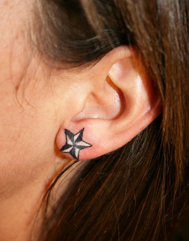 Creative ear tattoo featuring a black and white star on the lobe.