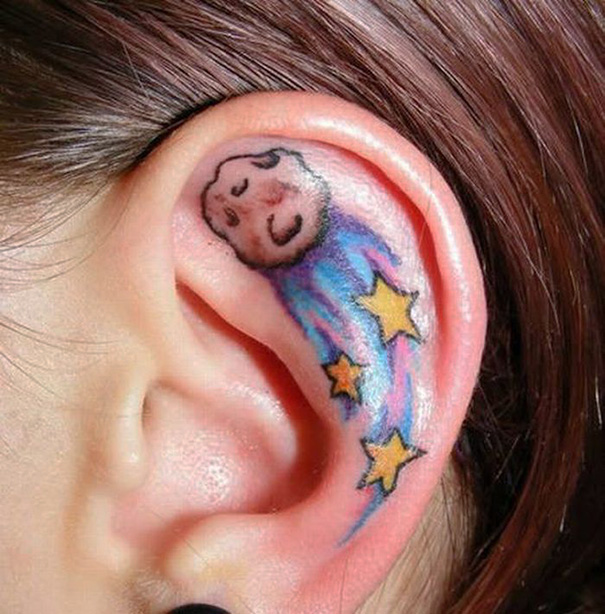 Creative ear tattoo featuring a sleeping moon and stars with colorful trails.
