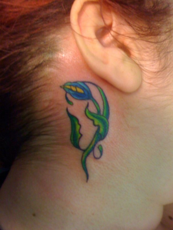 Colorful abstract ear tattoo design with blue and green elements.