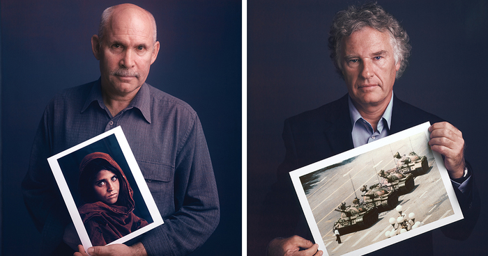 Two famous photographers posing with prints of their iconic images against a dark background.