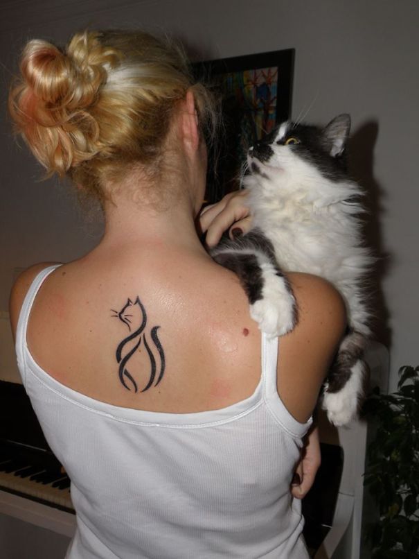 Woman with line art cat tattoo holding a black and white cat.