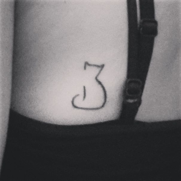 Minimalistic line art cat tattoo on skin.