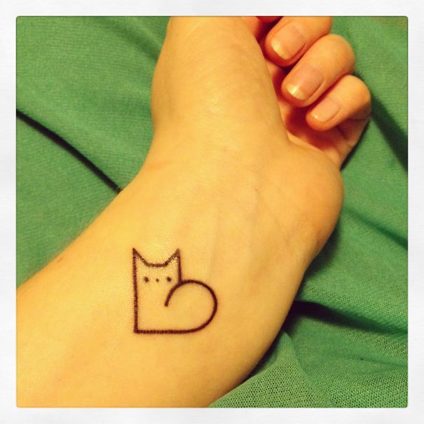 Simple line art cat tattoo on wrist, minimalist design for cat lovers.