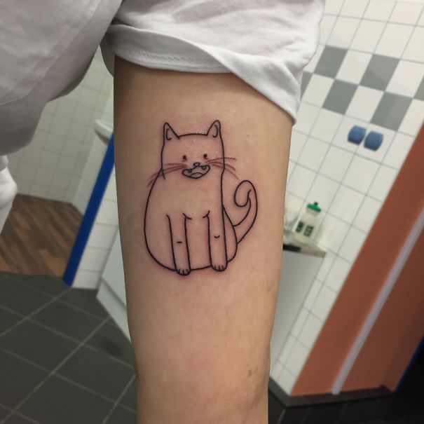 Line art tattoo of a simple cat design on a person's arm in a minimalistic style.