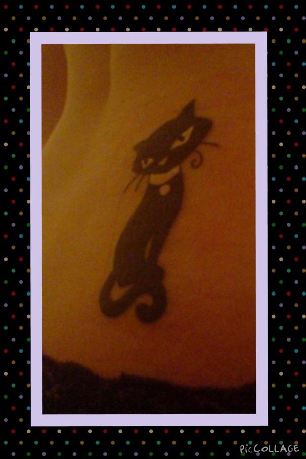 Simple line art cat tattoo design on skin, surrounded by a dotted border.