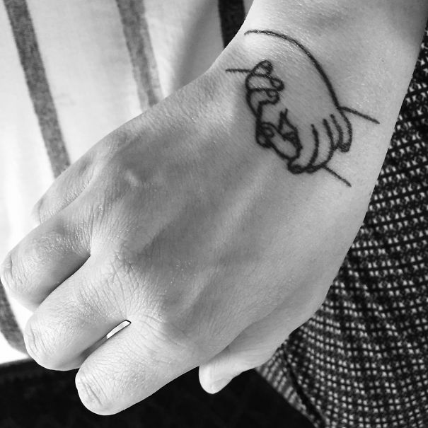Minimalist Picasso-inspired tattoo of two hands on a wrist.