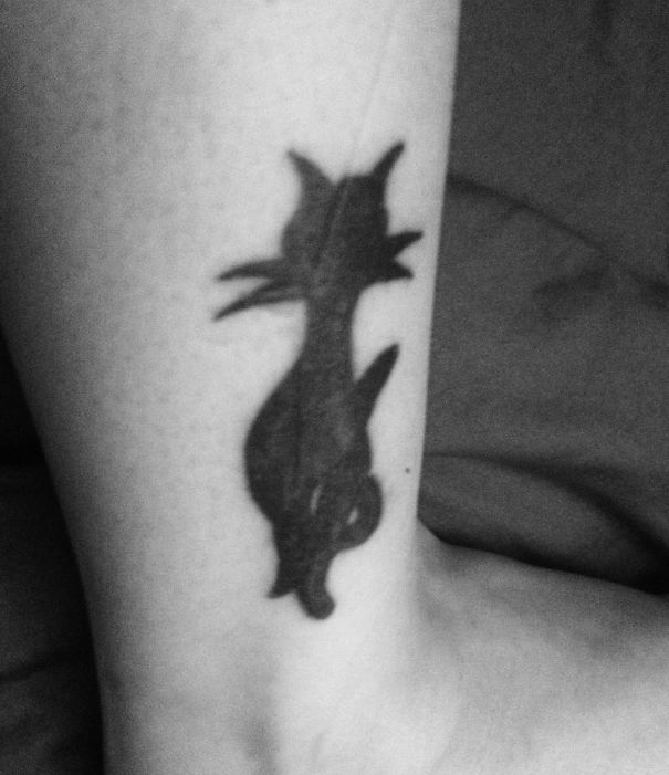Simple cat tattoo design in black line art on forearm.