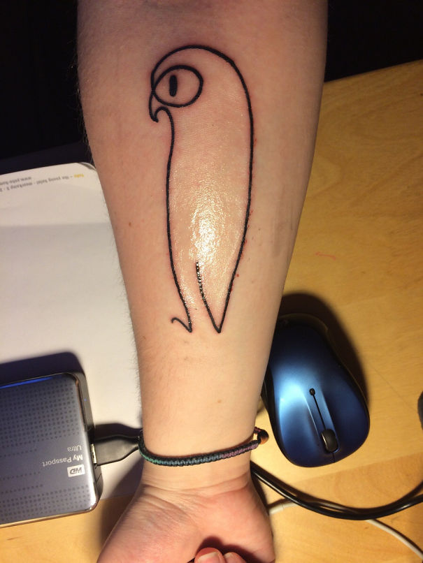 Minimalist Picasso-inspired tattoo of a bird on a person's forearm, next to a mouse and external hard drive.