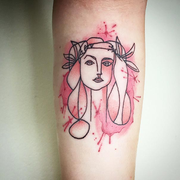 Abstract tattoo with Picasso-inspired face design and pink watercolor on forearm.