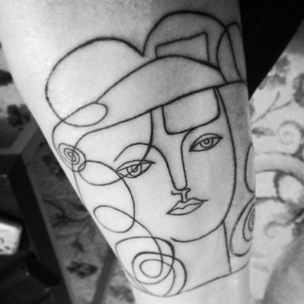 Picasso-inspired tattoo with abstract line art of a woman's face on skin.