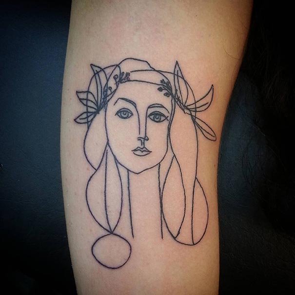 Picasso-inspired tattoo design on arm, featuring an abstract face outline.
