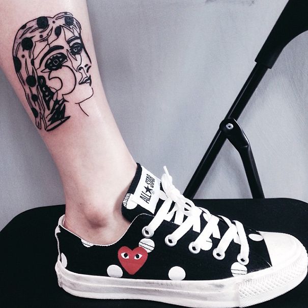 Picasso-inspired tattoo on leg, featuring abstract face, paired with polka dot sneakers.