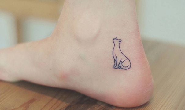 Line art cat tattoo on ankle, featuring a simple, minimalist design for cat lovers.