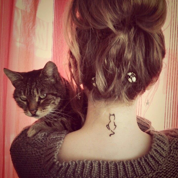 Woman with simple cat tattoo on neck, holding a tabby cat.