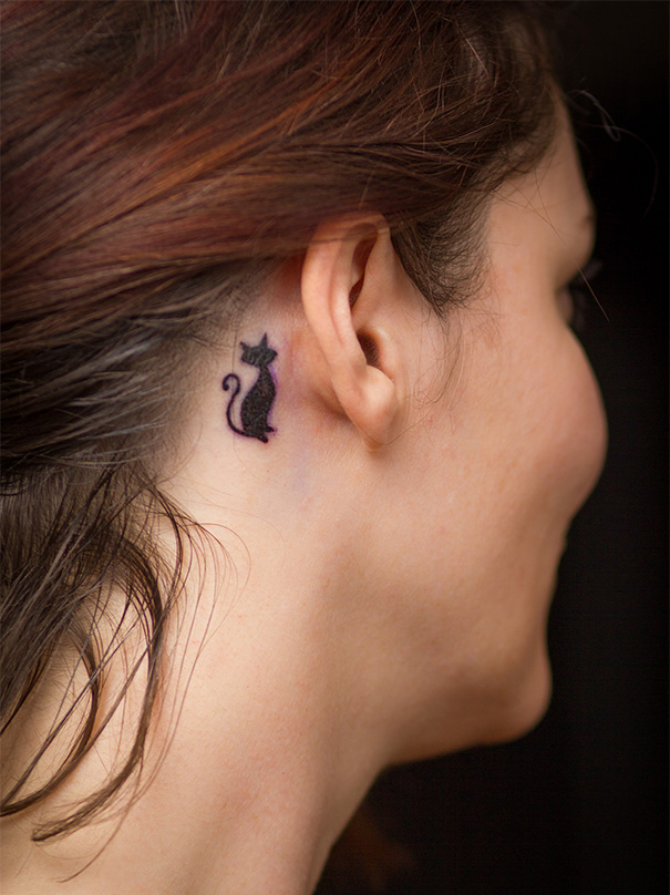 Line art cat tattoo behind ear, showcasing simple design for cat lovers.