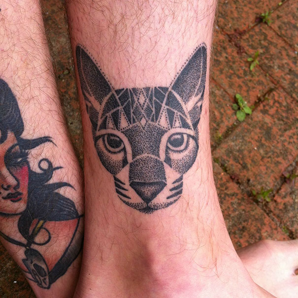 Line art cat tattoo on a person's leg, featuring geometric patterns and detailed dot work.