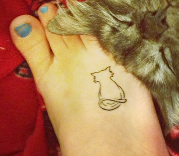 Simple cat tattoo design in line art on a person's foot.